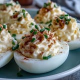 Freshly prepared Million Dollar Deviled Eggs with creamy filling, shown on a marble surface.