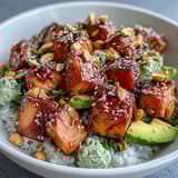 Colorful Avocado Salmon Bowl with sliced cucumbers, spring onions, and sesame seeds, served with lime wedges for a bright finish.
