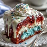 Colorful patriotic poke cake, swirled with gelatin and topped in white chocolate ganache.