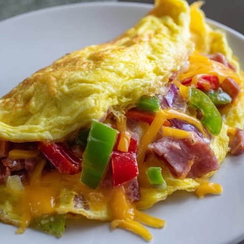 Fluffy Denver Omelet with a hint of onion, cheese oozing out, perfect for your breakfast.