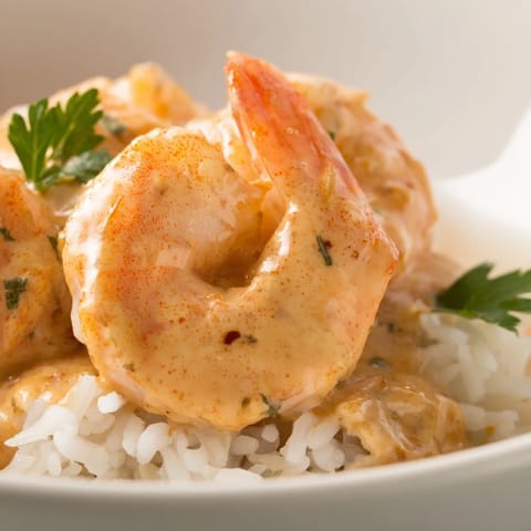 A close-up of the Creamy Cajun Shrimp Rice Bowl highlights tender shrimp coated in a velvety, Cajun-spiced sauce.